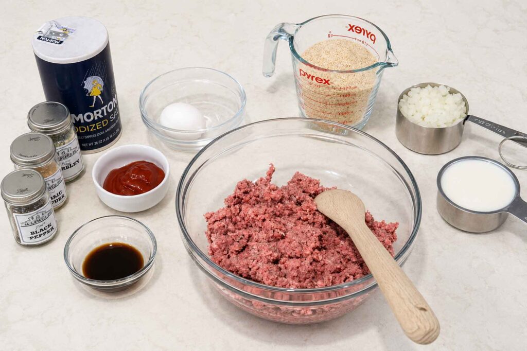 My best meatloaf ingredients, including spices, salt, worcestershire sauce, ketchup, egg, bread crumbs, onions, milk, and ground beef.
