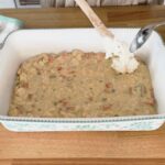 Spooning biscuit mix on top of the casserole