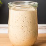 Active sourdough starter in a glass jar at its peak