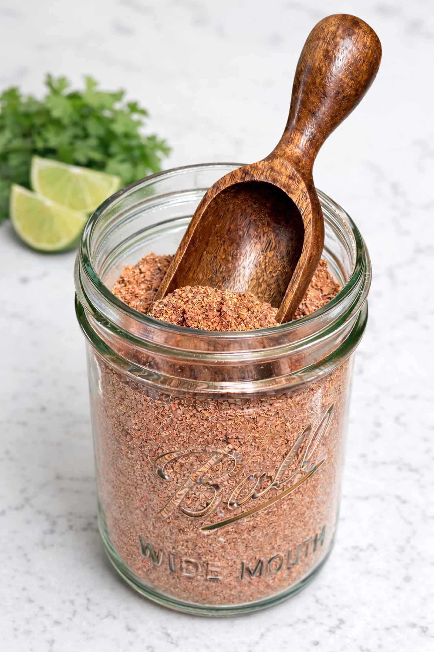 Homemade taco seasoning in a Mason jar with little scoop