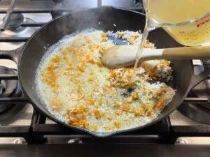 Adding broth to rice in skillet