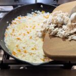 Adding chicken to skillet of rice