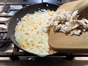 Adding chicken to skillet of rice