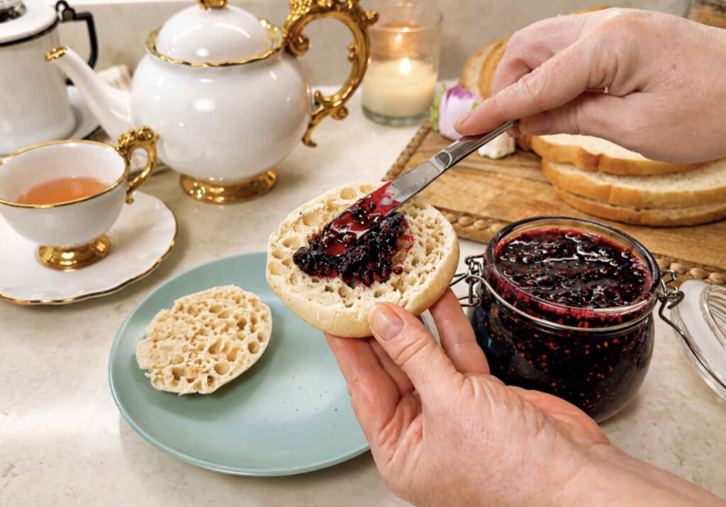 Spreading blackberry jam on a muffin