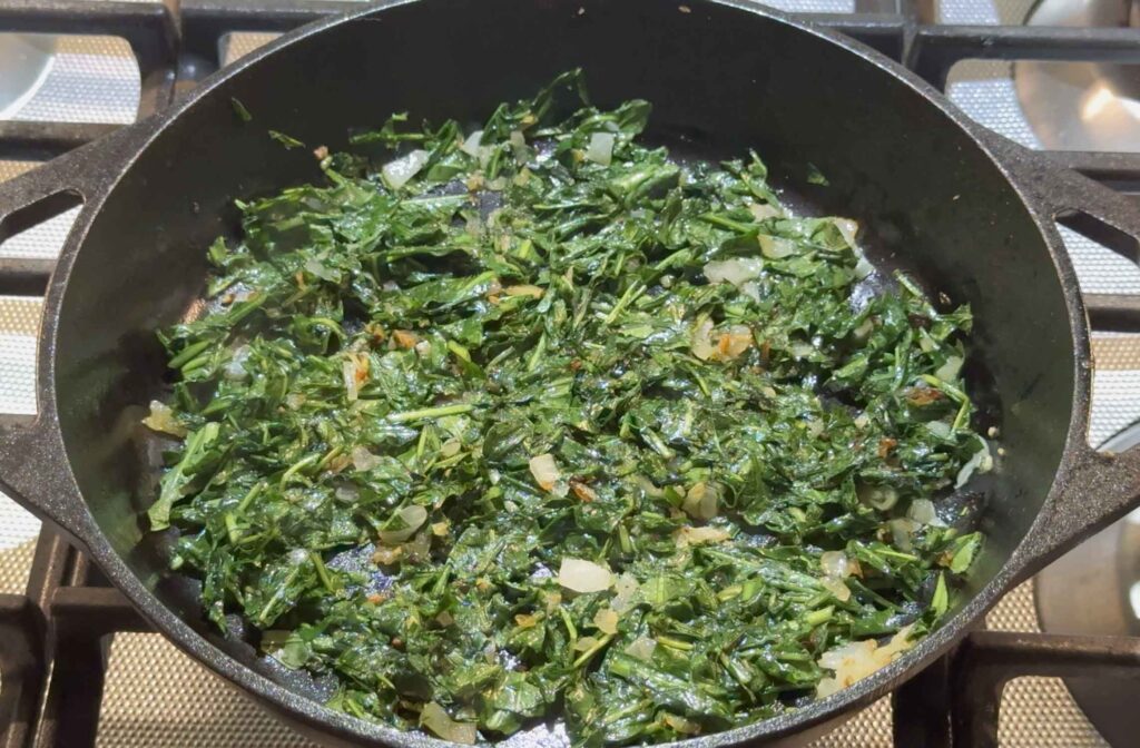 Frying dandelion greens in a cast iron skillet 