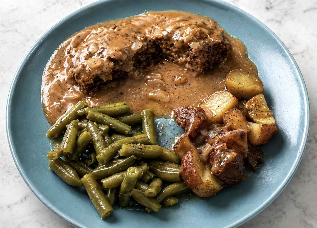 Salisbury steak on plate with potatoes and green beans