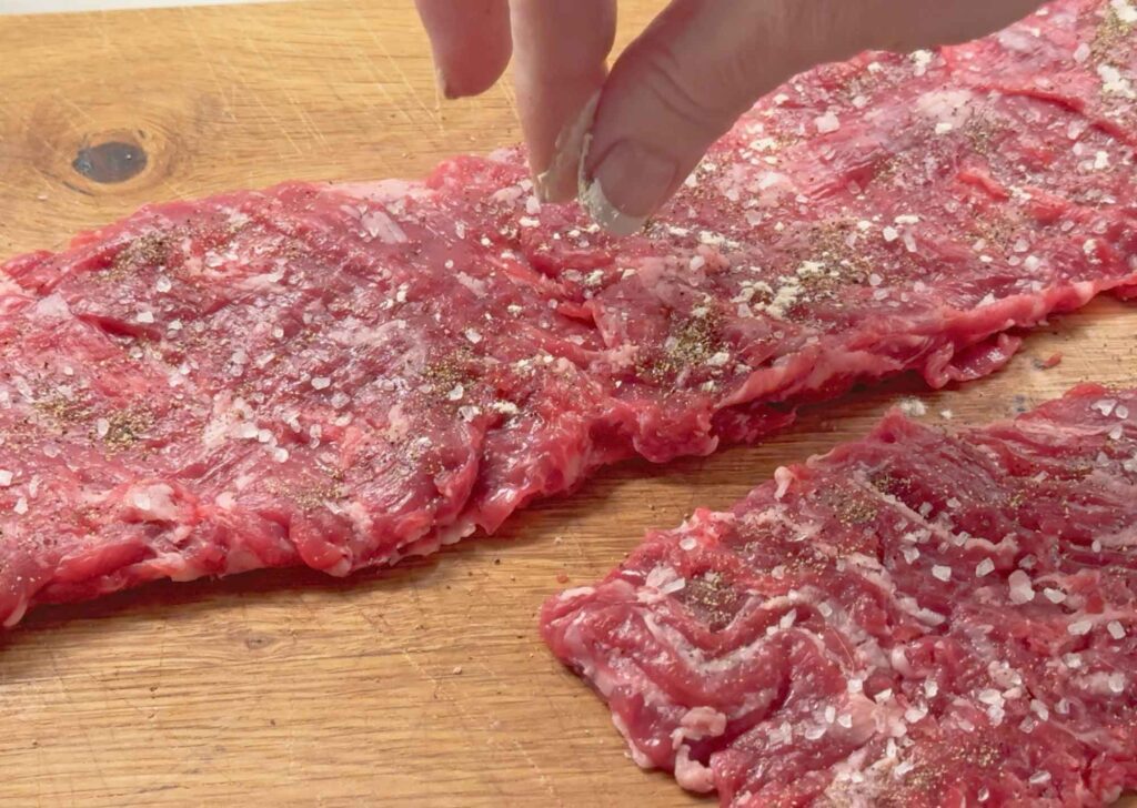 seasoning the skirt steak with salt, pepper, and garlic