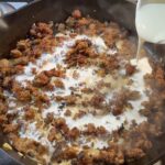 Adding cream to the browned meat in a skillet
