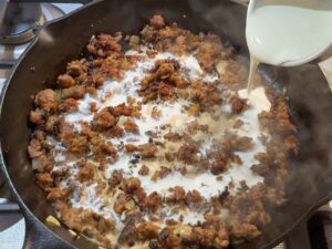 Adding cream to the browned meat in a skillet