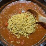 Adding uncooked macaroni to the pot of goulash