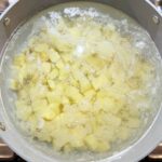 Boiling potato cubes in a pot of water, salt, and vinegar