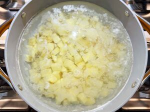 Boiling potato cubes in a pot of water, salt, and vinegar