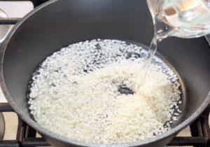 Adding water to rice in pot