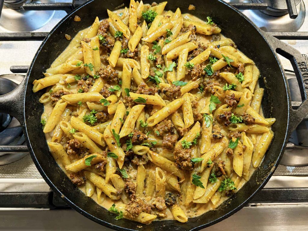 Creamy sausage pasta in a cast-iron-skillet on the stove