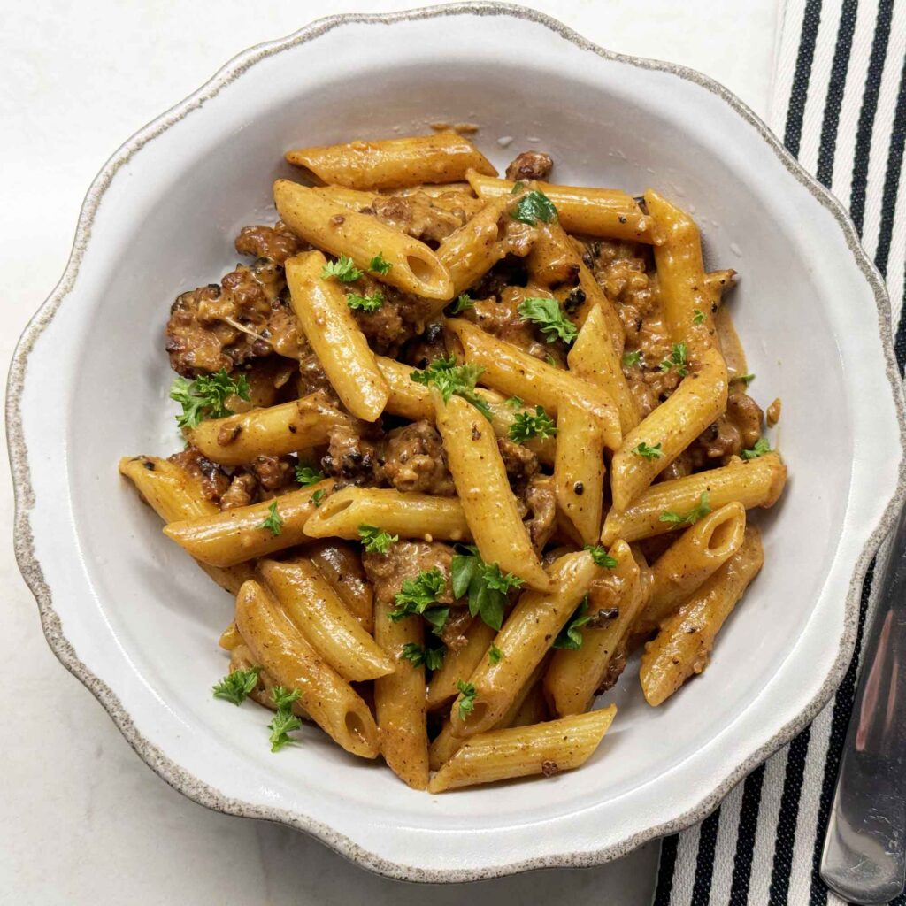 Creamy sausage pasta in a white bowl