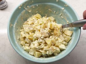 Folding in potatoes to make the salad