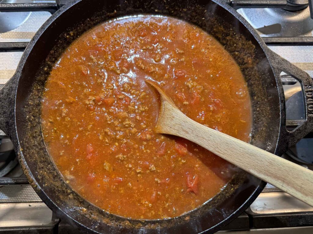 Tomato sauce and spices added to beef and onions