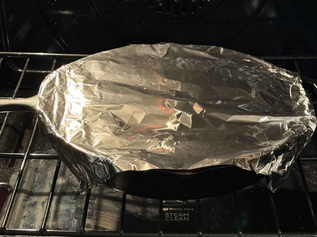 Hobo casserole covered with aluminum foil in oven