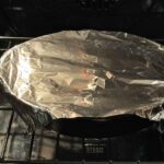 Hobo casserole covered with aluminum foil in oven