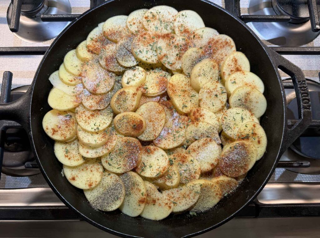 Potato slices and seasonings on top of the meat