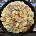 Sliced potatoes and seasonings in the skillet