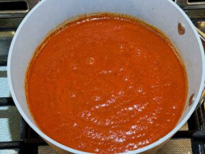 Tomato sauce simmering in enchilada sauce in pan