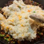 Spreading mashed potatoes over meat filling