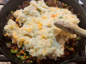 Spreading mashed potatoes over meat filling