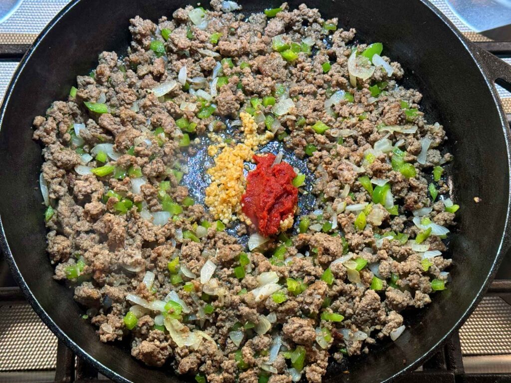 Adding garlic and tomato paste to the meat mixture