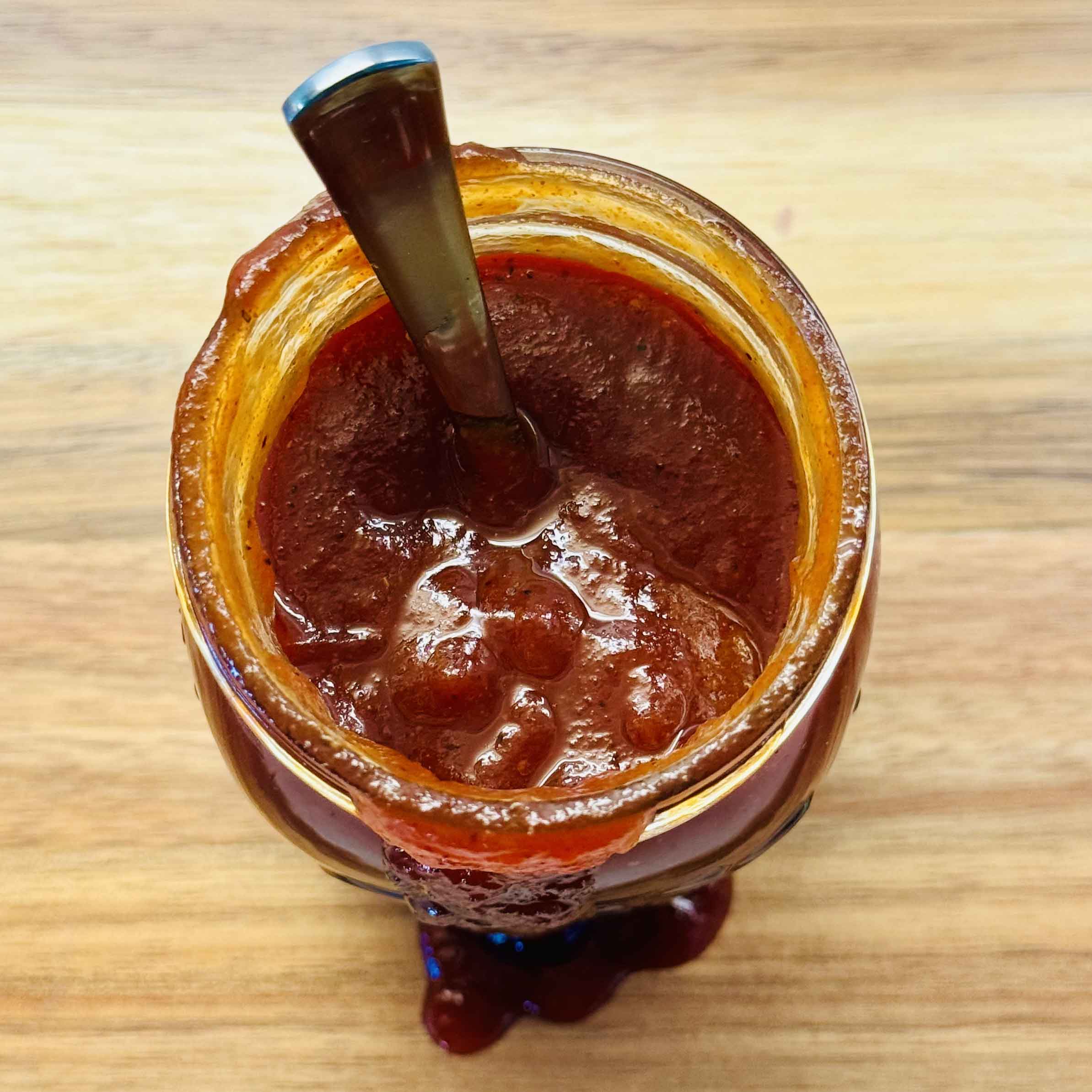 A jar of homemade BBQ sauce in use
