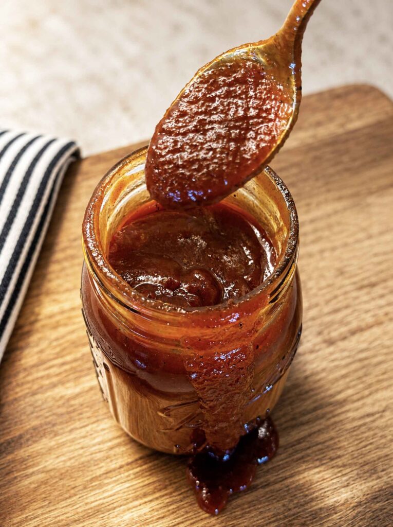 Spooning out some bbq sauce from a jar