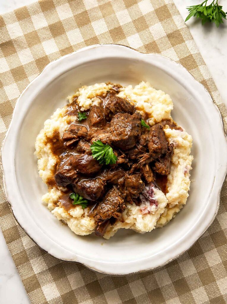 Beef tips over mashed potatoes in a bowl
