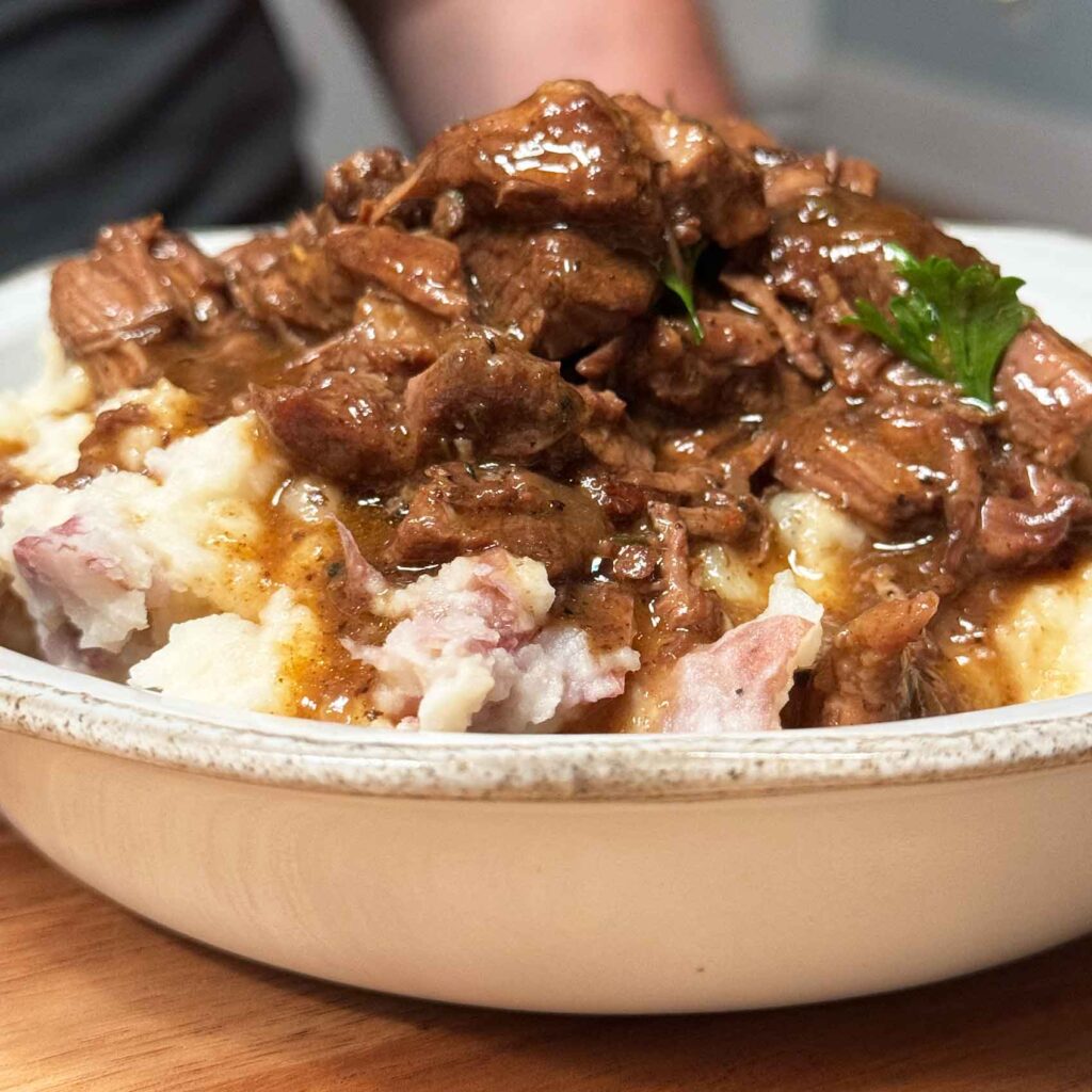 Beef tips and gravy piled on top of creamy red skin mashed potatoes