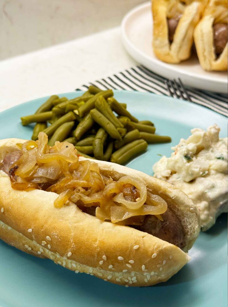 Beer brats on a plate with potato salad and green beans