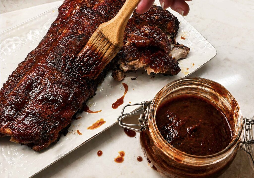 Brushing bbq sauce on ribs before serving