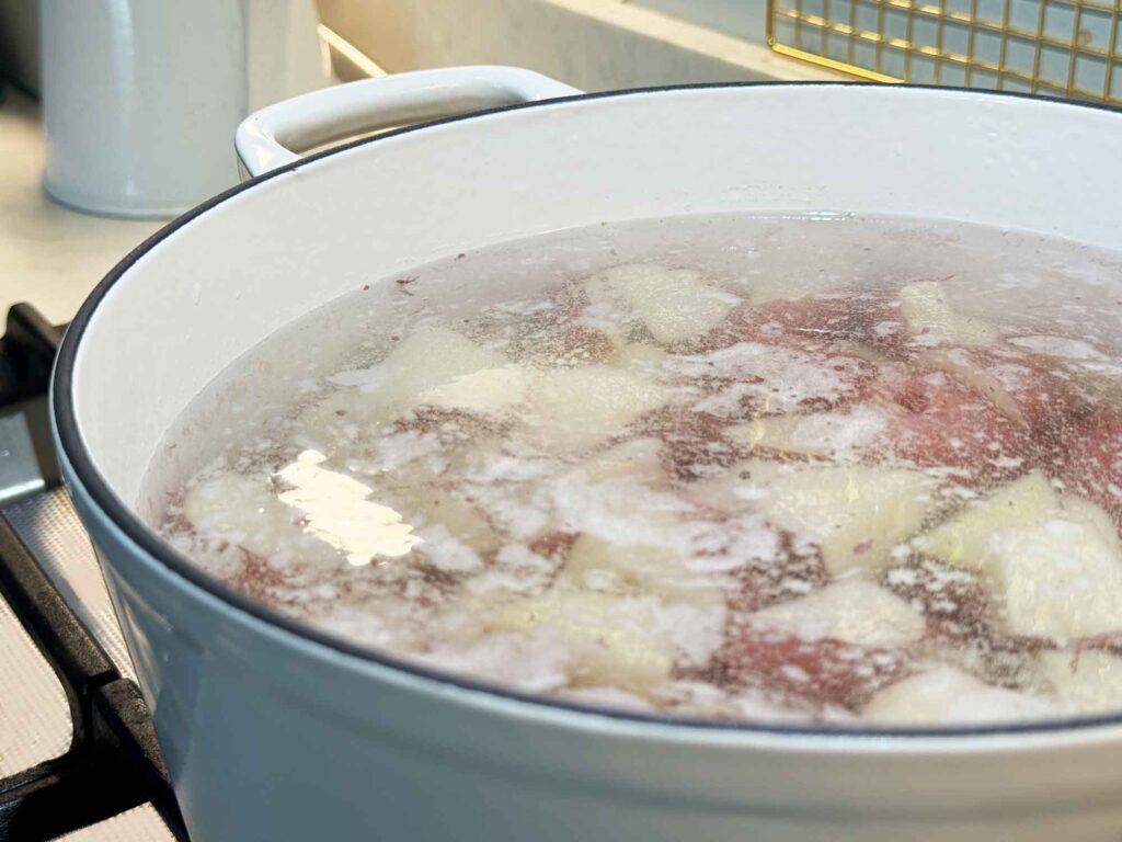 Cold water over potatoes in a pot