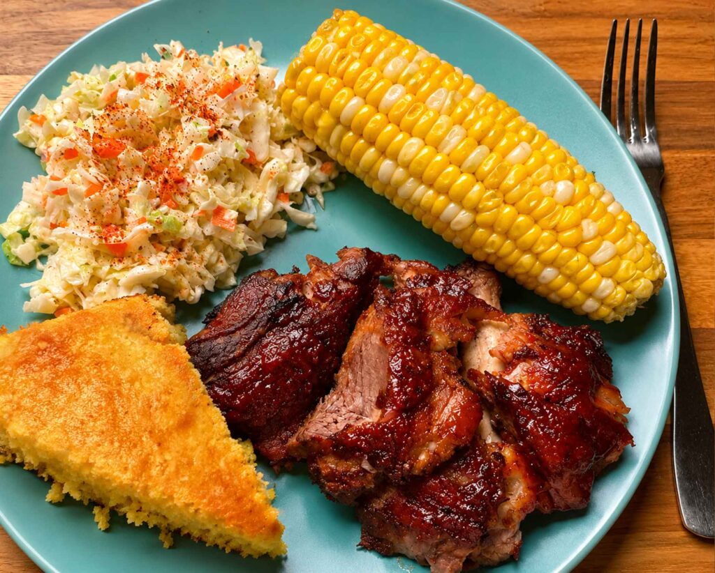 Cornbread, bbq ribs, coleslaw, and corn on the cob