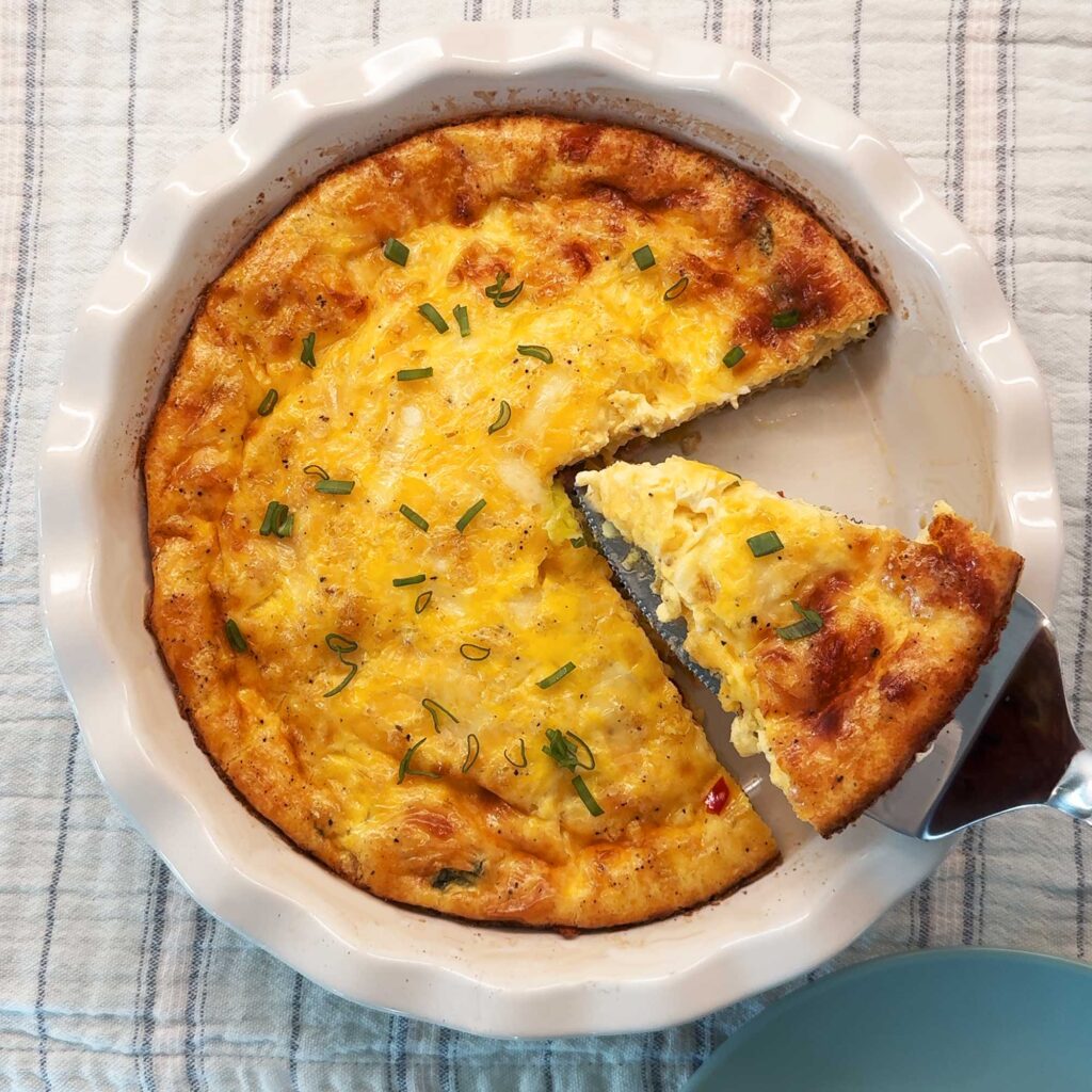 Crustless quiche in a pie dish with a piece being served