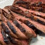 Sliced easy steak marinade flat iron steak fanned on a white platter, showing a juicy pink medium interior and seared crust.