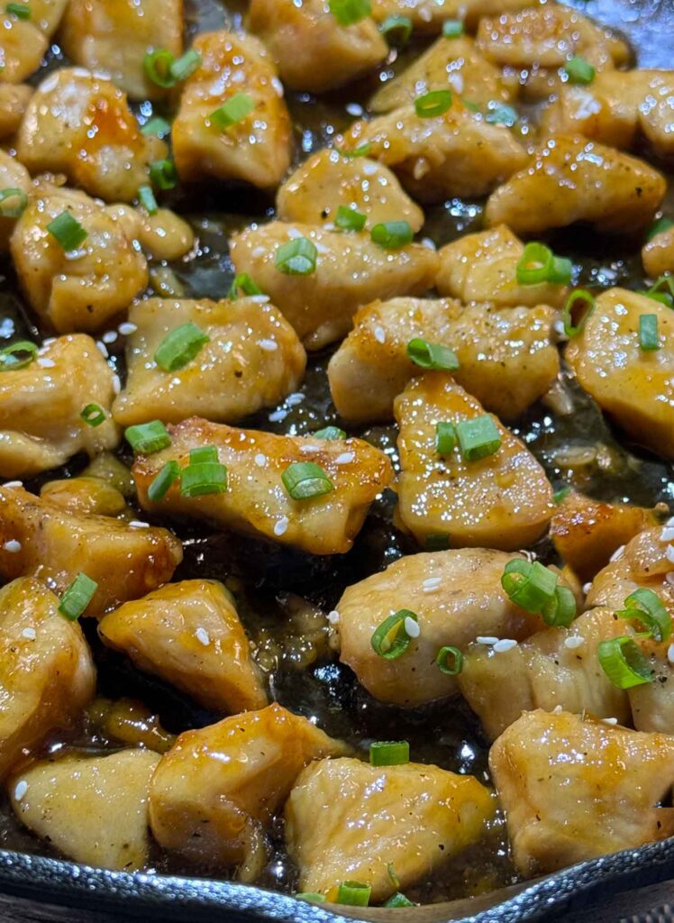 Finished honey garlic chicken in the skillet with green onions and sesame seeds