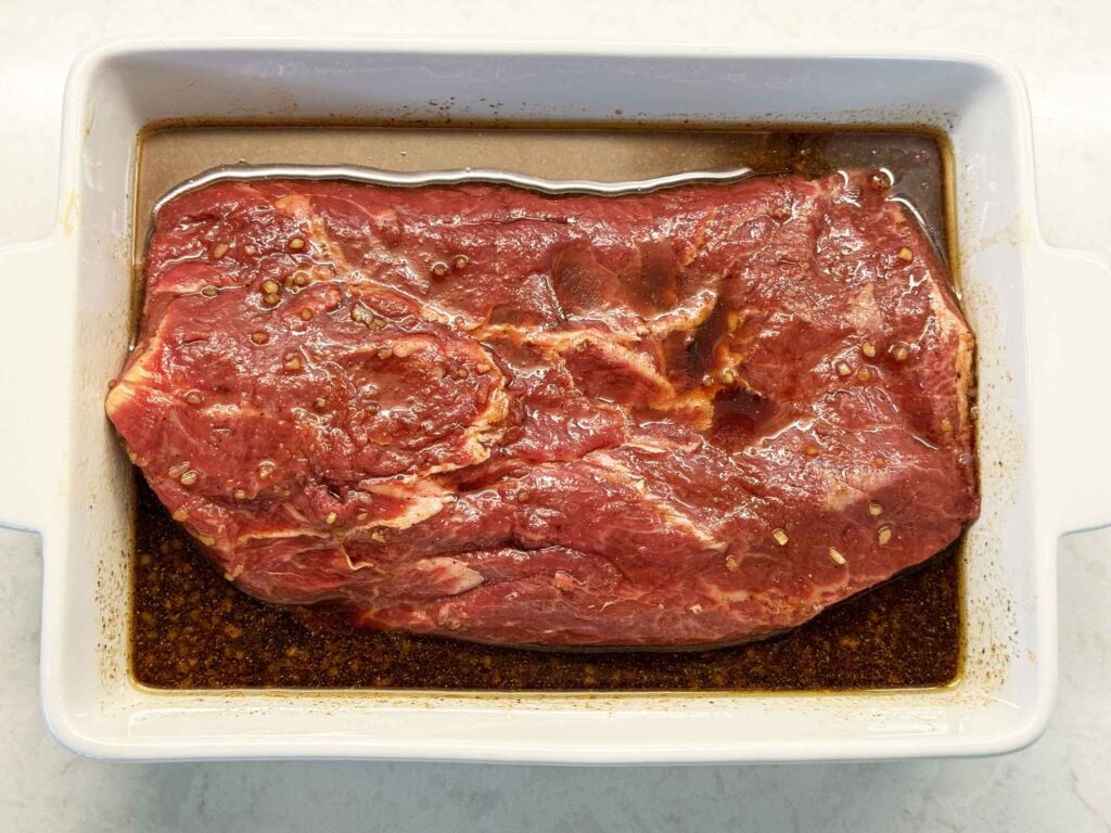 A steak marinating in the steak marinade mix in a shallow dish