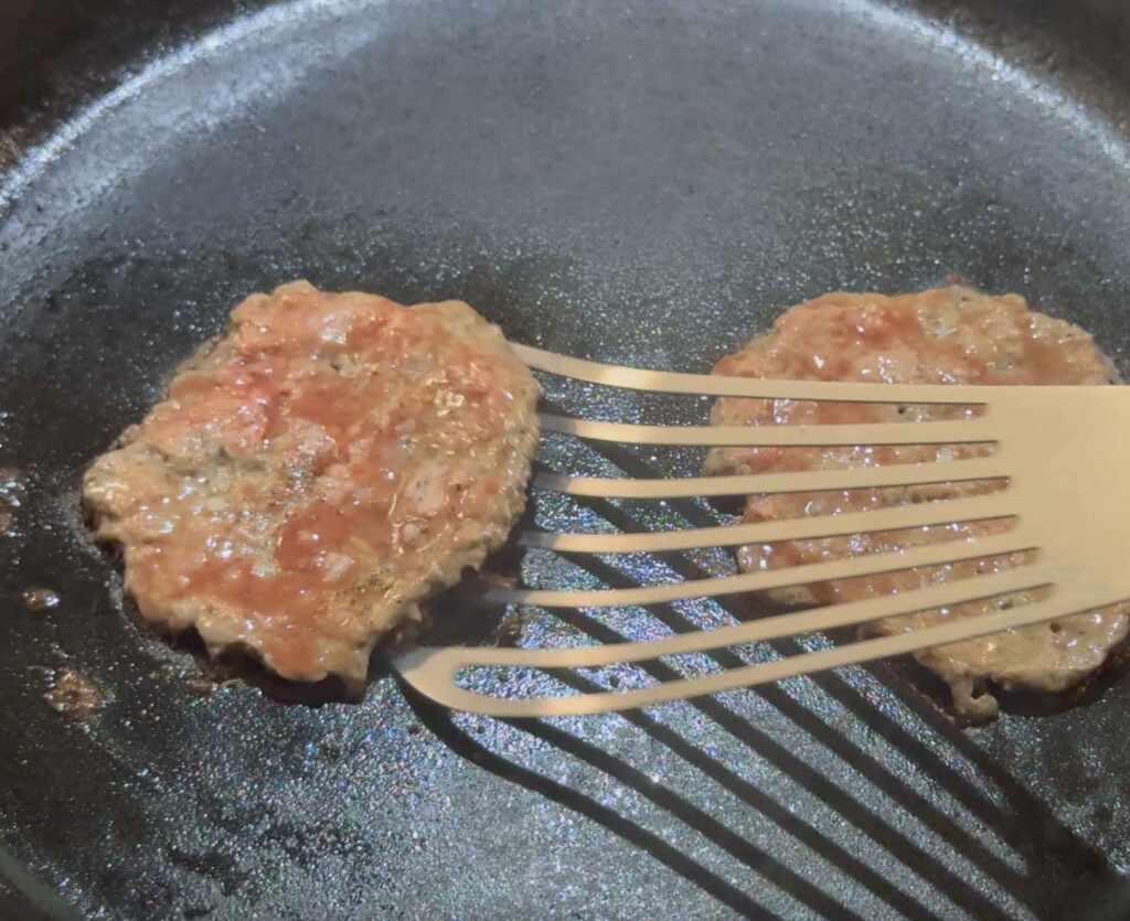 Flipping the smash burgers over in the pan