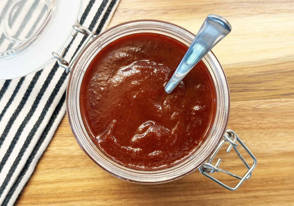 Homemade bbq sauce in a jar on a cutting board
