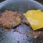 Placing cheese on the smash burgers