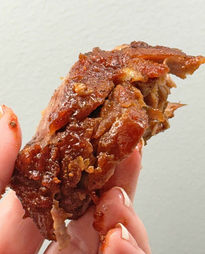A piece of oven baked bbq ribs, saucy and messy