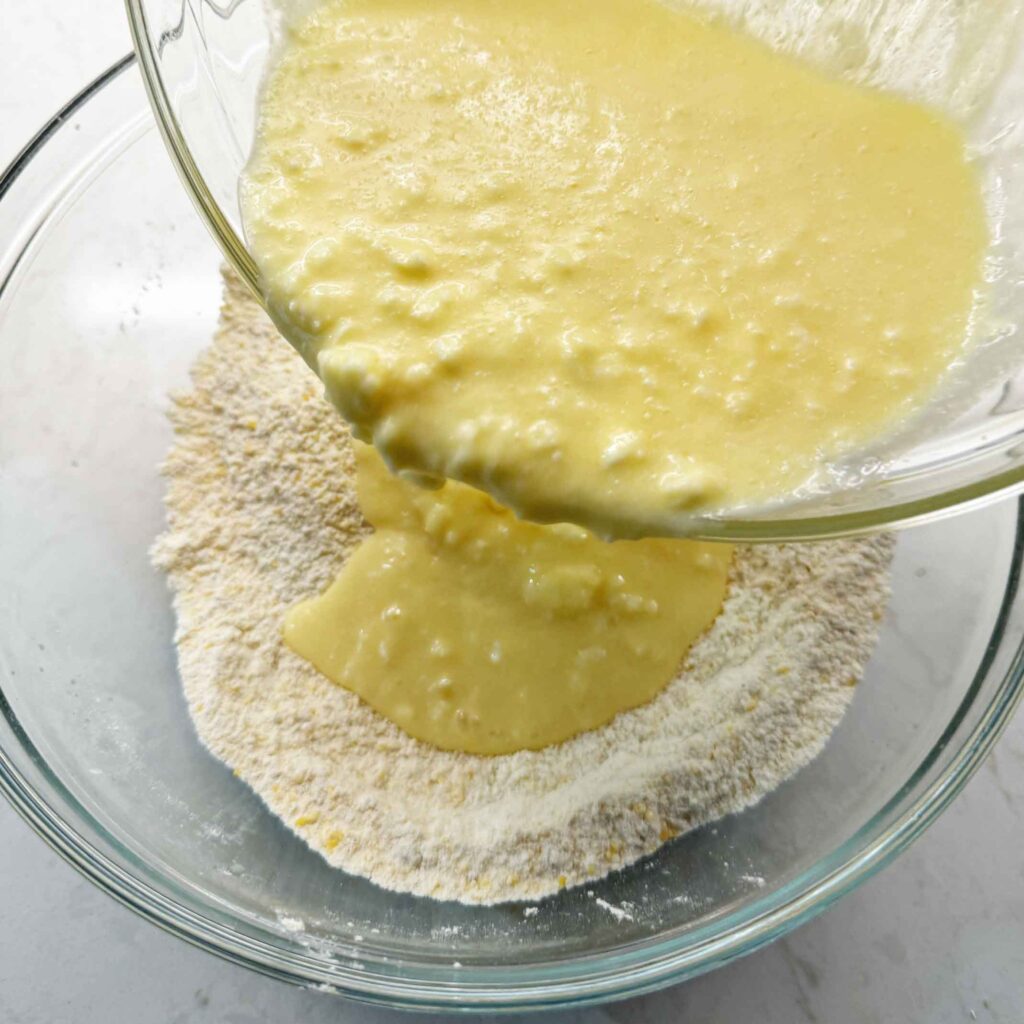 Pouring wet ingredients into dry ingredients to make cornbread