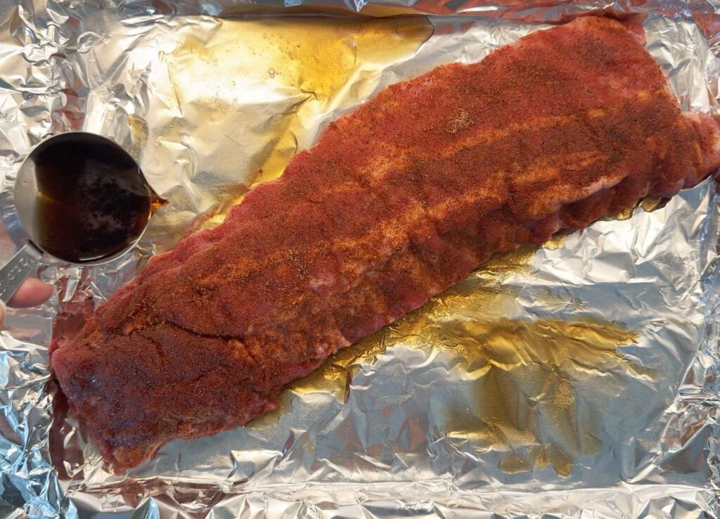 Pouring Coke near the ribs on a baking sheet