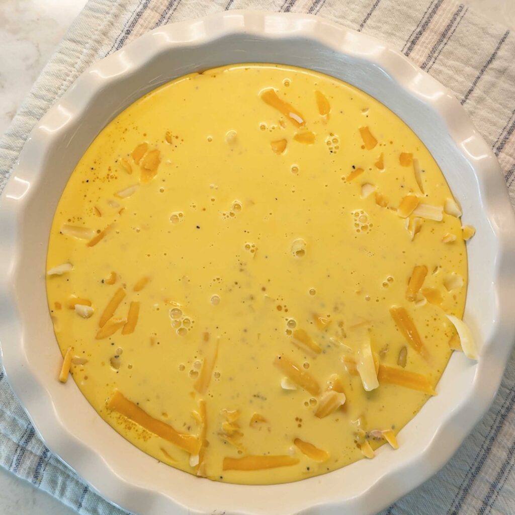 Egg and dairy filling poured into the quiche layers