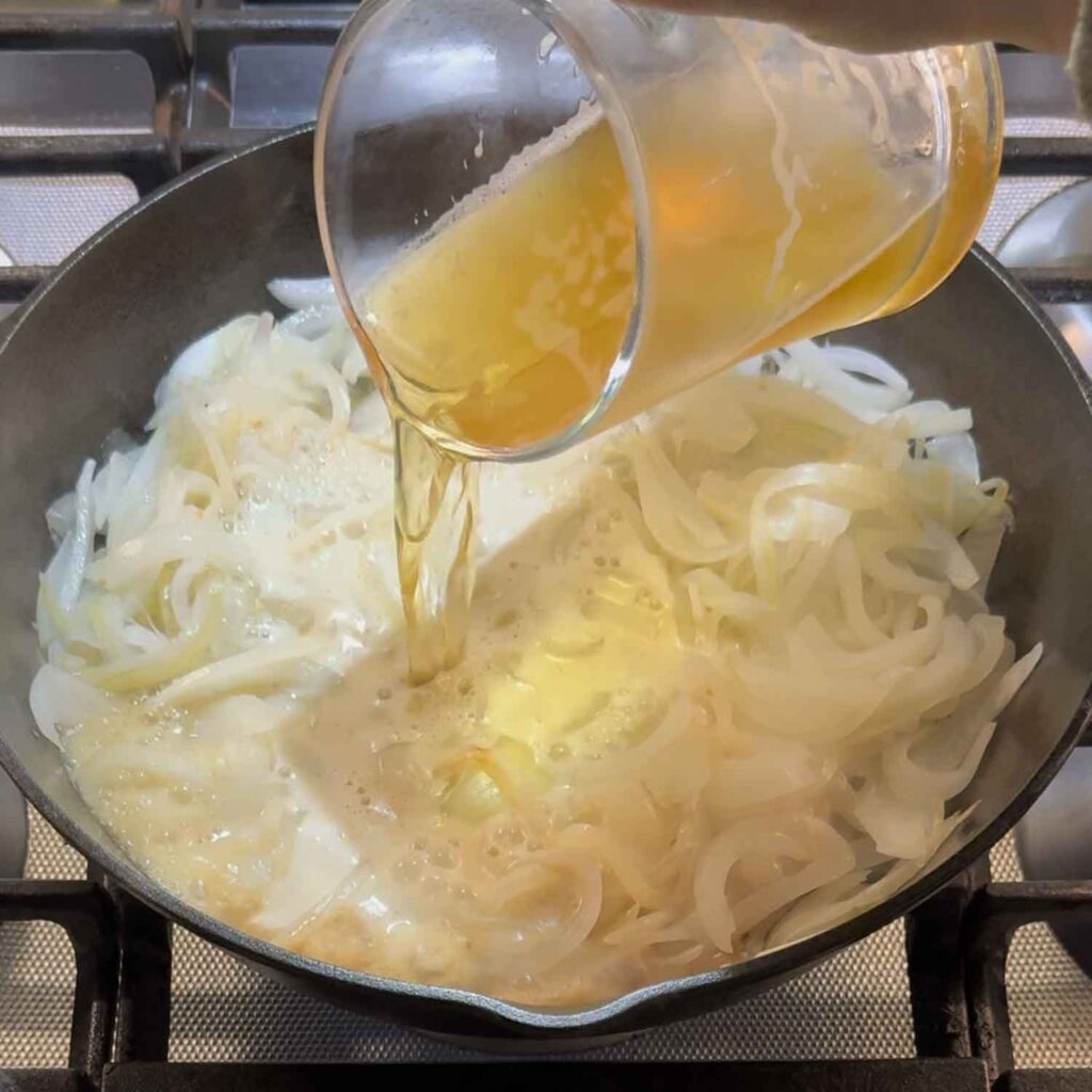 Pouring beer into skillet with onions