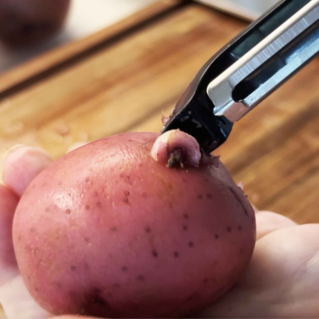 Removing an eye from a potato with the tip of a potato peeler